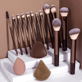 Set of makeup brushes and beauty sponges on a white platform with a brown background